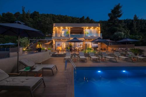 a house with a swimming pool at night at Anmian Suites in Vourvourou