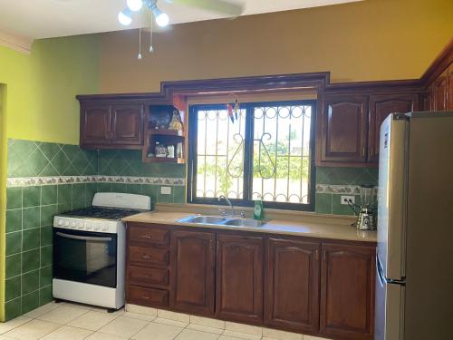 a kitchen with wooden cabinets and a sink and a window at Villa Victoria in La Romana