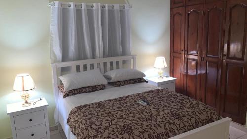 a bedroom with a bed with two night stands and two lamps at Villa Victoria in La Romana