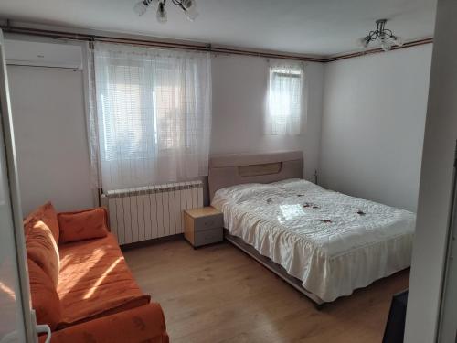 een slaapkamer met een bed en een bank erin bij Apartman Anastasija in Surčin