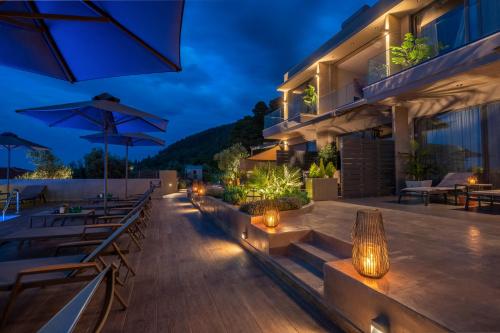 a hotel patio with tables and umbrellas at night at Anmian Suites in Vourvourou