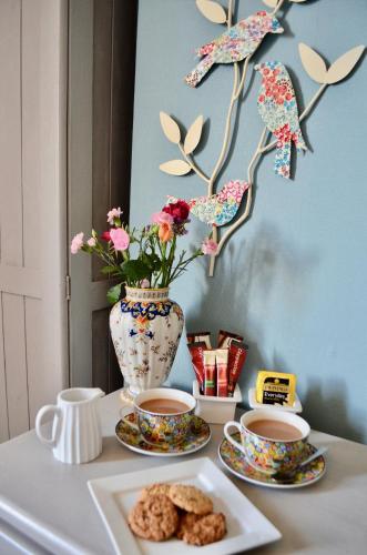 a table with two cups of coffee and a vase with flowers at St George's Guest House in York