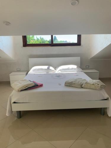 Cama blanca en habitación con ventana en Casa vacanze rosario, en Vena Superiore