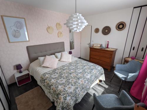 ein Schlafzimmer mit einem Bett, einem Stuhl und einem Kronleuchter in der Unterkunft Au Beau Bouquet in Avremesnil