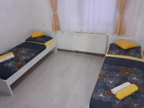 2 letti in una piccola camera con cuscini gialli di Apartman Dalal - with access to river Una a Bihać