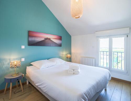 - une chambre avec un grand lit blanc et un mur bleu dans l'établissement Les Duplex du Lac d'Orient, à Mesnil-Saint-Père