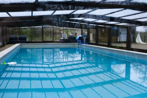 an indoor swimming pool with blue water at Les Cabanes de Brassac in Brassac