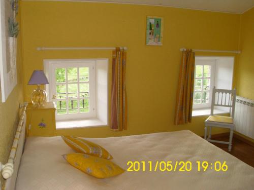 a bedroom with a bed with yellow walls and windows at Chambre d'hôtes MISTRAL in Villard