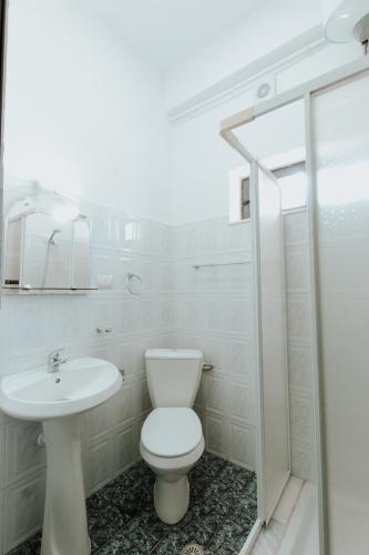 a white bathroom with a toilet and a sink at HOTEL LUNXHERIA in Gjirokastër