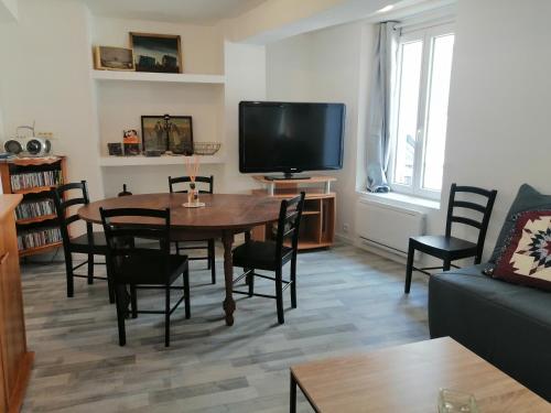 a living room with a table and chairs and a tv at F Logement entier in Courtenay