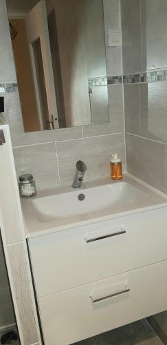 La salle de bains est pourvue d'un lavabo avec miroir et d'une bougie. dans l'établissement L'Hermitage - Piscine et Bien-être, à Saint-Nectaire