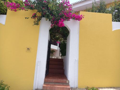 a yellow and white house with a door with flowers at Alojamento Local Largo da Igreja in Santiago do Cacém