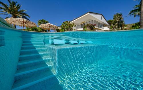 a swimming pool with blue water and umbrellas at La Moraleja The Quiet Hotel - Adults Only in Cala de Sant Vicenc