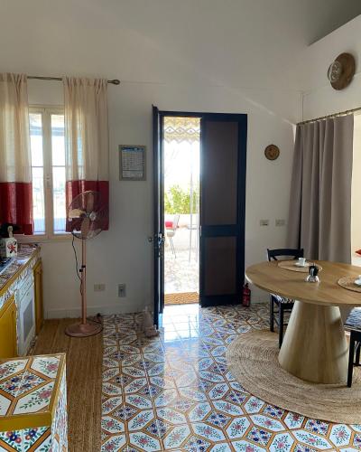 a living room with a table and a door to a patio at Dammuso Pensare alla Luna in Pantelleria
