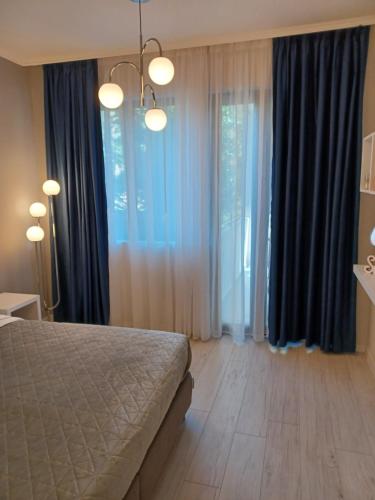 a bedroom with blue curtains and a bed with a wooden floor at Tara Deluxe Apartment in Varna City