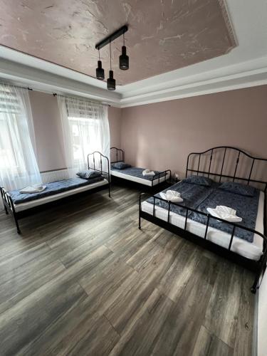 two beds in a room with wooden floors and windows at Dzintari in Ventspils