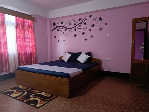 a bedroom with a bed with a tree sticker on the wall at Wind Valley Homestay in Pelling