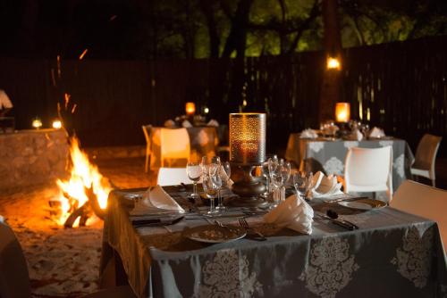 a table set up for a meal in front of a fire at Moditlo River Lodge in Hoedspruit