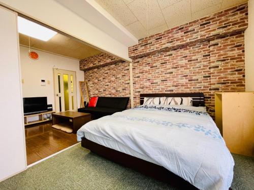a bedroom with a brick wall and a bed at 新規OPEN！サービスアパ―トメントSAPPORO中島公園302 in Sapporo