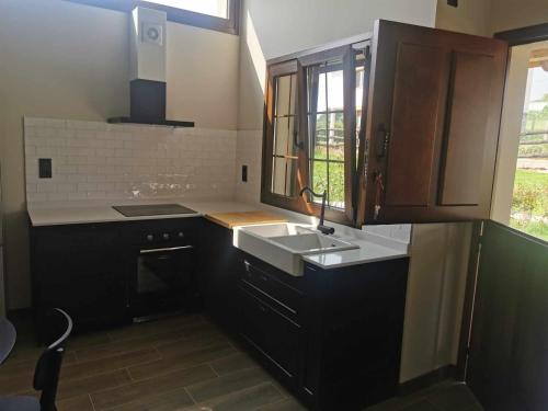 a kitchen with black cabinets and a sink and a window at La campa de FaedoTere in Cudillero