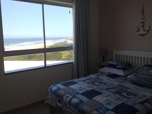 a bedroom with a bed and a large window at Afsaal Holiday Flats in Amanzimtoti