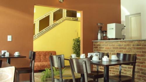 une salle à manger avec deux tables et un mur jaune dans l'établissement Hotel Aries Palermo, à Buenos Aires