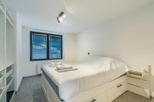 a white bedroom with a bed and a window at Design Studio Gent modern en stijlvol met terras in Ghent