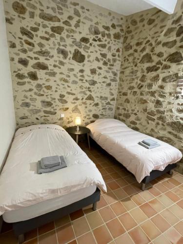- 2 lits dans une chambre aux murs en pierre dans l'établissement Gîte de la Foye - Le Lilas, à Combrand