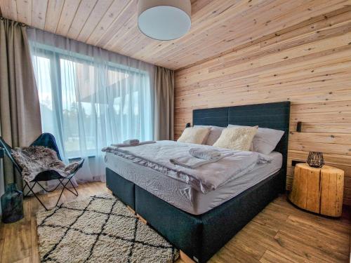 1 dormitorio con 1 cama y pared de madera en Chalet STRÖMY Demänovská dolina en Liptovský Mikuláš