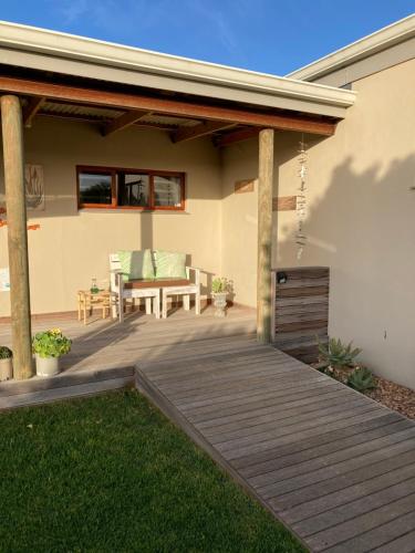 a patio with a wooden deck with a bench on it at Waves Of Witsand in Witsand