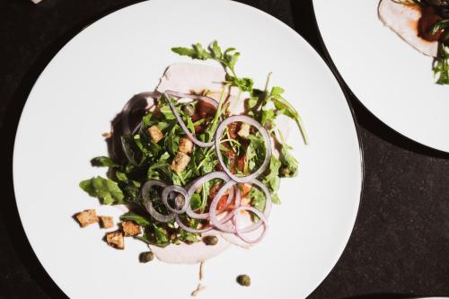 a white plate with a salad with onions on it at Bretterhotel in Brienz