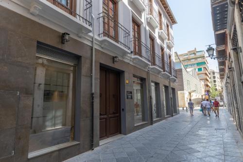 a street with buildings and people walking down the street at BiBo Suites San Agustín in Granada