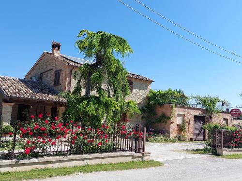 una casa con una valla y flores rojas en Casale San Martino Agriturismo Bio, en SantʼAngelo in Pontano