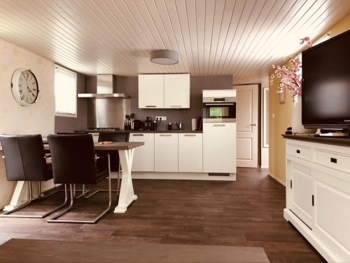 a kitchen with white cabinets and a table with chairs at Vakantiehuis “Het Zeepaard” in Voorthuizen