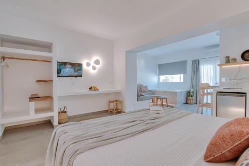 a white bedroom with a large bed and a kitchen at Nautica suites - Executive suite with jacuzzi in Antiparos