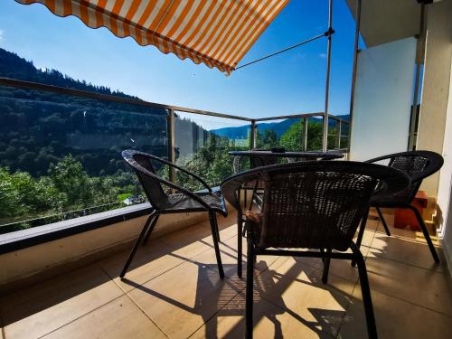 two chairs and a table on a balcony with a view at Orchid Luxury Apartment Sinaia in Sinaia