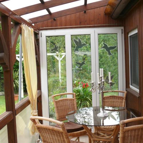 un porche cubierto con mesa de cristal y sillas en Bungalow im Märchengarten, en Krauschwitz