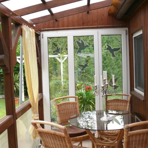 a screened in porch with a glass table and chairs at Bungalow im Märchengarten in Krauschwitz