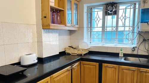a kitchen with a counter and a sink and a window at The Aster Homestay - Bedrooms & Apartments in Kolkata