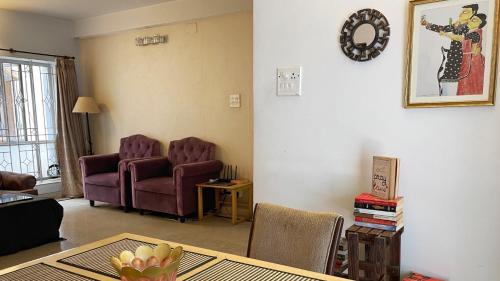a living room with two chairs and a table at The Aster Homestay - Bedrooms & Apartments in Kolkata
