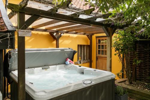 bañera de hidromasaje en un patio trasero con pérgola de madera en Oak Cottage, en Thorndon