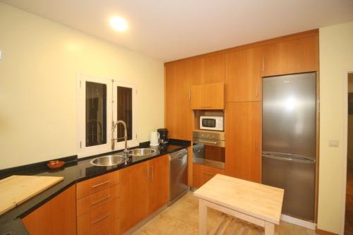 a kitchen with wooden cabinets and a stainless steel refrigerator at Casa da Quintã Gerês by Gerês Casas in Vieira do Minho