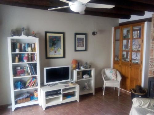 un salon avec une télévision et une étagère blanche dans l'établissement Casa Rural la Escalera, à Letur