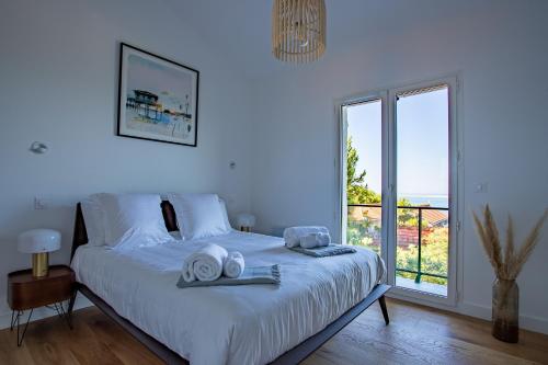a white bedroom with a bed with towels on it at O'DYSSEE Appartement vue panoramique Bassin d'Arcachon in Pyla-sur-Mer