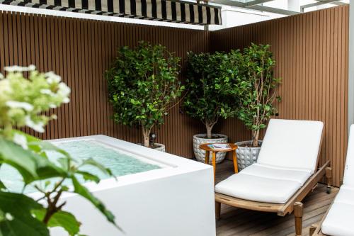 a patio with a hot tub and a chair and potted trees at BLESS Hotel Madrid - The Leading Hotels of the World in Madrid