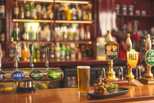 una barra de bar con una copa de cerveza y un plato de comida en The Exmoor Forest Inn, en Simonsbath