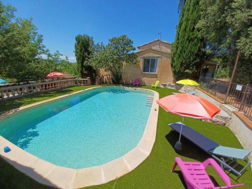 une piscine avec un parasol et deux chaises roses et un parasol dans l'établissement Bastide Saint Romain, à Salernes