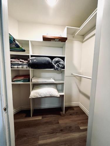 um closet com prateleiras brancas e pisos de madeira em Cozy Private Bed & Bath near Medical Center, Galleria and DT em Houston