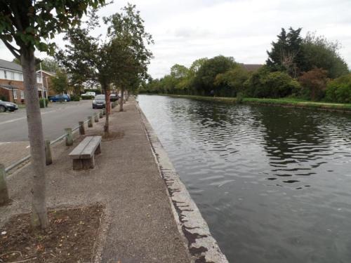 a river with a bench next to a street at Vibrant Single Room only for one adult in Southall