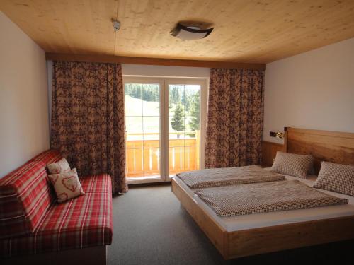 sypialnia z łóżkiem, kanapą i oknem w obiekcie Berggasthof Schatzbergalm w mieście Thierbach